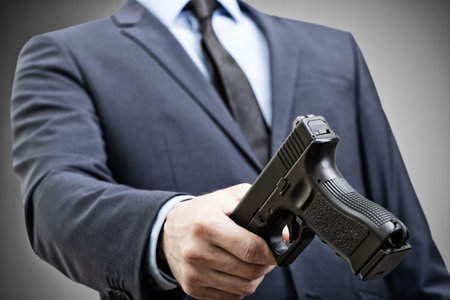 White man in suit holding handgun in hand and trying to pass it to someone