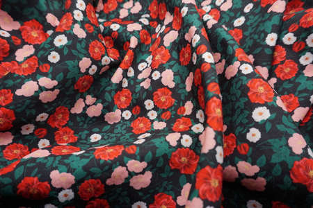 The texture of the fabric is dark green with red flowers on a black backgroundの写真素材