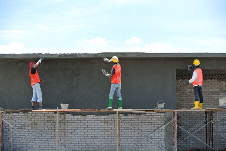 Group of skill construction workers plastering wall using cement plaster at construction site.のeditorial素材