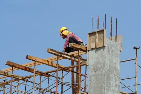 A construction workers installing beam formwork. Formwork is located at the high level that requires the workers to use scaffolding.のeditorial素材