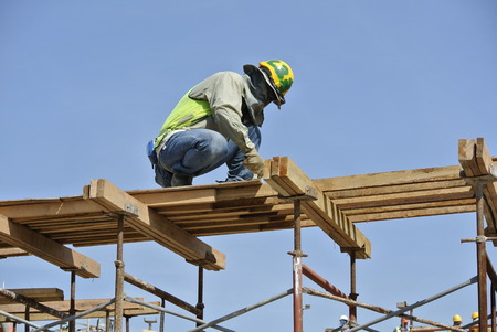 A construction workers installing beam formwork. Formwork is located at the high level that requires the workers to use scaffolding.のeditorial素材