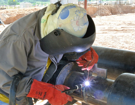 A licensed welders welding pipe. He is hired to do welding work on the pipeline.