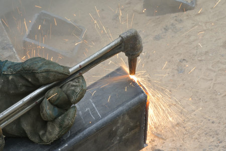 Workers at construction site cutting metal using blowtorch. Blowtorch produced very high temperature...