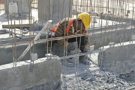 A construction workers hacking reinforce-concrete ground beam using hacker tool on July 03, 2014 at Sepang, Selangor, Malaysia.のeditorial素材