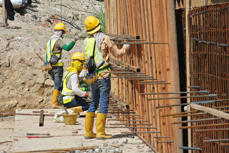 Construction workers fabricate retaining wall reinforcement bar and formwork at the construction...