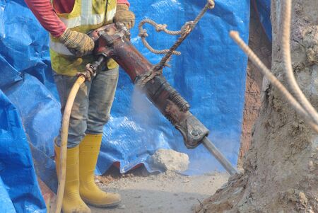 CYBERJAYA, MALAYSIA  MARCH 20, 2015: A construction workers using concrete hacker to cut concrete pile at the construction site.のeditorial素材