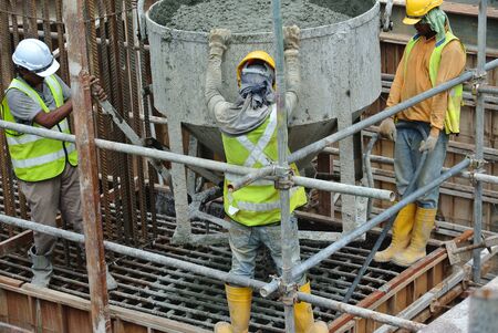 SELANGOR, MALAYSIA  SEPTEMBER 2014: A group of construction workers pouring concrete using concrete bucket into the pile cap formworkのeditorial素材