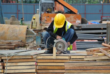 JOHOR, MALAYSIA  SEPTEMBER 15, 2015: A construction worker using the portable all purpose pipe cutter machine to cut piece of woods at the construction site in Johor, Malaysia on September 15, 2015.のeditorial素材