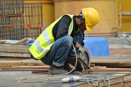 JOHOR, MALAYSIA  SEPTEMBER 15, 2015: A construction worker using the portable all purpose pipe cutter machine to cut piece of woods at the construction site in Johor, Malaysia on September 15, 2015.のeditorial素材