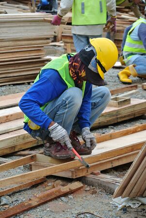 MALACCA, MALAYSIA  SEPTEMBER 28, 2015: Carpenter worker fabricating timber formwork at the construction site in Malacca, Malaysia on September 28, 2015.のeditorial素材