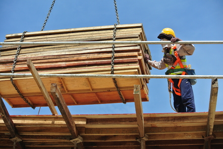 SELANGOR, MALAYSIA  DECEMBER 09, 2015: Group of construction workers lifting bundle of timber using mobile crane at the construction site on December 09, 2015.のeditorial素材