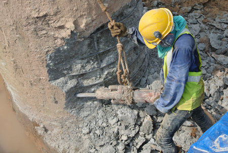 Construction worker using mobile concrete hacker to hack concrete pile at the construction site