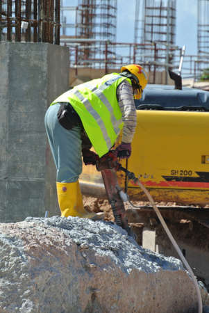 JOHOR, MALAYSIA -JANUARY 13, 2015: A construction workers cutting foundation pile using hacking method at the construction site. He using the heavy duty mobile hacker machine.のeditorial素材