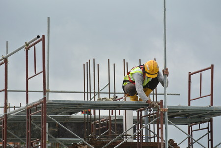 PERAK, MALAYSIA -JULY 18, 2016: Construction workers wearing safety harness and installing scaffolding at high level in the construction site.のeditorial素材