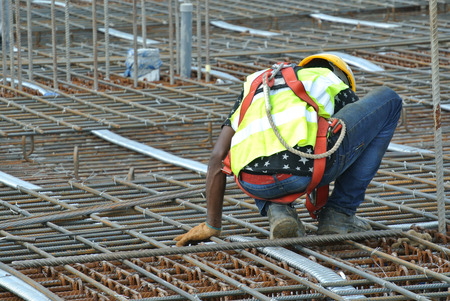 MALACCA, MALAYSIA -JUNE 27, 2016: Construction workers fabricating steel reinforcement bar at the construction site in Malacca, Malaysia. The reinforcement bar was ties together using tiny wire.のeditorial素材