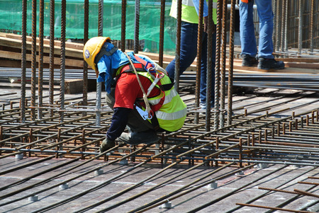 MALACCA, MALAYSIA -JUNE 27, 2016: Construction workers fabricating steel reinforcement bar at the construction site in Malacca, Malaysia. The reinforcement bar was ties together using tiny wire.のeditorial素材