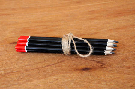Black pencils tied with a rope of straw yarn. Against the backdrop of plywood wood pattern.の写真素材