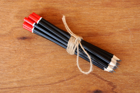 Black pencils tied with a rope of straw yarn. Against the backdrop of plywood wood pattern.の写真素材