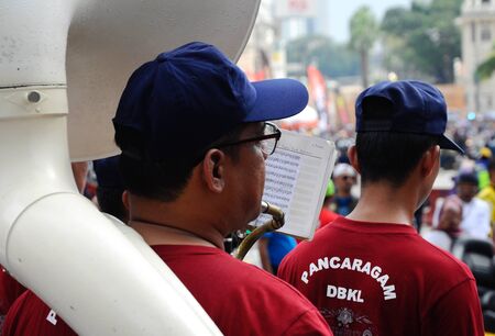 KUALA LUMPUR, MALAYSIA -FEBRUARY 22, 2017: Brass band player is playing a musical instrument while guided by musical notes.のeditorial素材