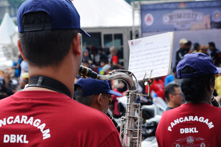 KUALA LUMPUR, MALAYSIA -FEBRUARY 22, 2017: Brass band player is playing a musical instrument while guided by musical notes.のeditorial素材