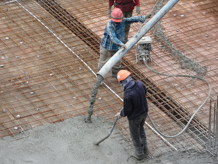 KUALA LUMPUR, MALAYSIA -JUNE 16, 2017: Construction workers pouring wet concrete using concrete...