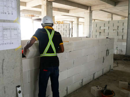 SEREMBAN, MALAYSIA -MARCH 17, 2020: Blockwork by construction workers at the construction site. Workers laying the AAC brick and stacked it together using mortar to form the wall.のeditorial素材