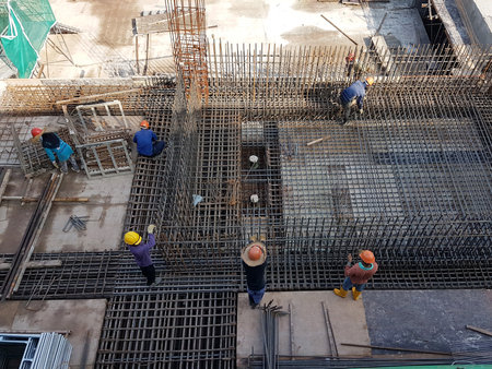IPOH, MALAYSIA -JUNE 23, 2020: Construction workers fabricating steel reinforcement bar at the construction site. They tied it using the tiny wires before covering it up with timber formwork.の写真素材