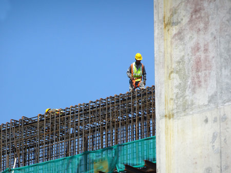MALACCA, MALAYSIA -MARCH 2, 2020: Construction workers working at height install reinforcement bars at the construction site. They are supplied with harnesses and other safety equipment.の写真素材