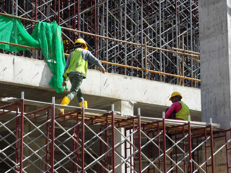 MALACCA, MALAYSIA -MARCH 2, 2020: Construction workers working at height install reinforcement bars at the construction site. They are supplied with harnesses and other safety equipment.の写真素材
