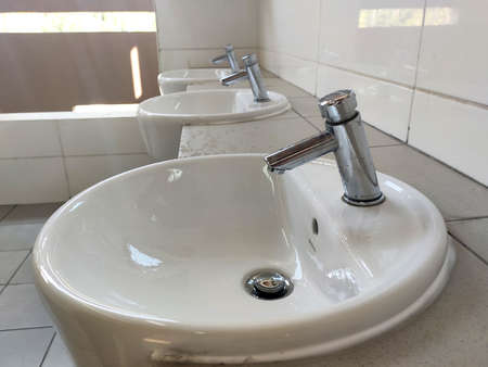 SEREMBAN, MALAYSIA -APRIL 1, 2020: Hand washbasins at the public toilet. Installation complete with face mirror. Made from white glazed ceramic.のeditorial素材