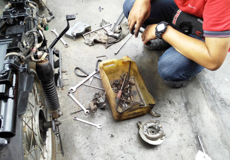 SEREMBAN, MALAYSIA -AUGUST 3, 2019: Mechanics are repairing and replacing motorcycle lubricants at the workshop. Each motorcycle will be serviced by one mechanic.のeditorial素材