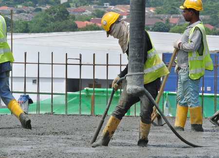 SELANGOR, MALAYSIA -JULY 13,2016: A group of construction workers pouring raw concrete using...