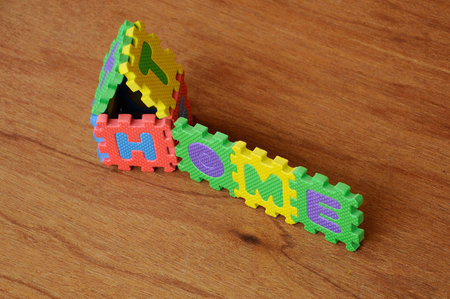 HOME word made from colourful soft rubber mat. Isolated on a wood texture board background.の写真素材