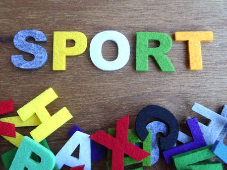SPORT word made from colorful felt fabric isolated on wood texture board.の写真素材