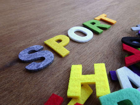 SPORT word made from colorful felt fabric isolated on wood texture board.の写真素材