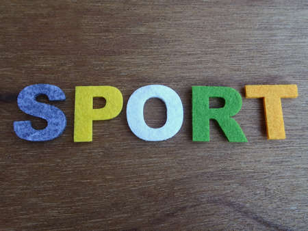 SPORT word made from colorful felt fabric isolated on wood texture board.の写真素材