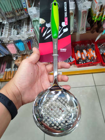PENANG, MALAYSIA -MARCH 4, 2021: Spoons, ladles and other cooking utensils are hung and displayed for sale. Each one is priced for the convenience of buyers.のeditorial素材