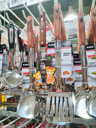 PENANG, MALAYSIA -MARCH 4, 2021: Spoons, ladles and other cooking utensils are hung and displayed...