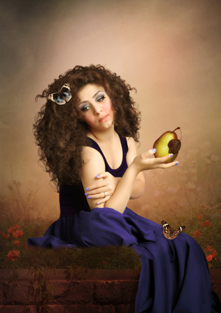 The young girl with long hair holding pear in the handの写真素材
