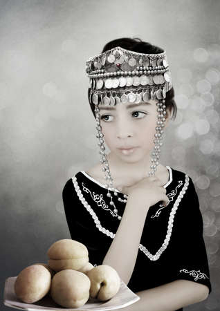 Girl in Armenian national clothes and a taraz headdress, with apricots in a vaseの写真素材