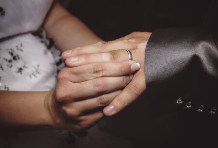 Close up hands of bride and groom putting on a wedding ringsの写真素材