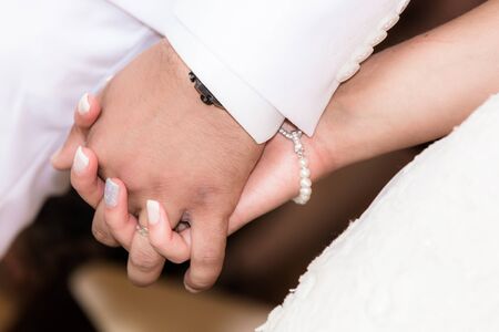 Close up of bride and groom holding hands during the marriage ceremonyの写真素材