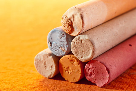 Closeup photograph of color chalks on bright yellow background.