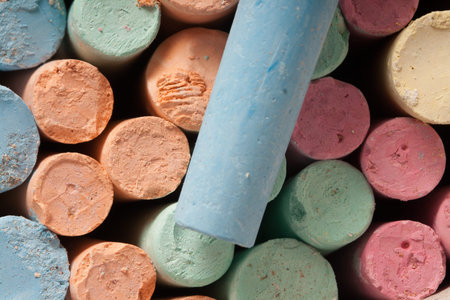 Closeup photograph of colored chalks on chalk background.