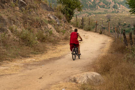 A monk riding on bicycle at a remote place in Bhutan.のeditorial素材