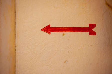 Painted red arrow closeup on yellow concrete wallの写真素材