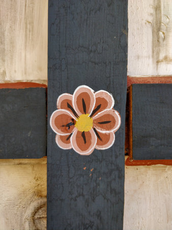Handmade flower decoration on a rustic wooden background with contrasting textures and colors.の写真素材