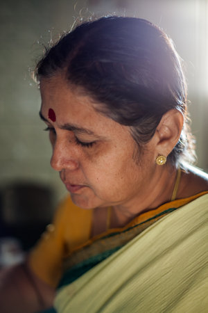 A close-up of a smiling woman with a red bindi on her forehead backlit by a warm, soft light.の写真素材