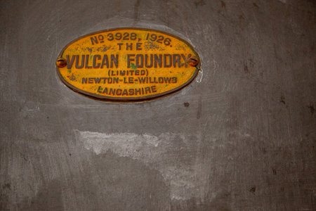 A yellow and black label with the word Vulcan on it. The label is attached to a metal surface