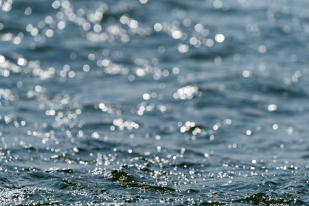 Blue water with ripples on the surface defocus blurred blue colored clear calm water surface texture with splashes and bubbles water waves with shining pattern texture backgroundの写真素材
